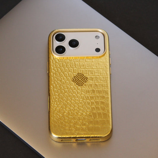 Gold phone case with crocodile texture on a reflective surface