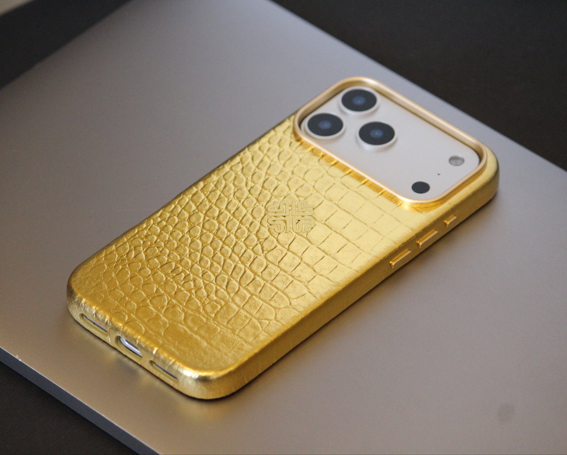 Gold phone case with crocodile texture on a metallic surface