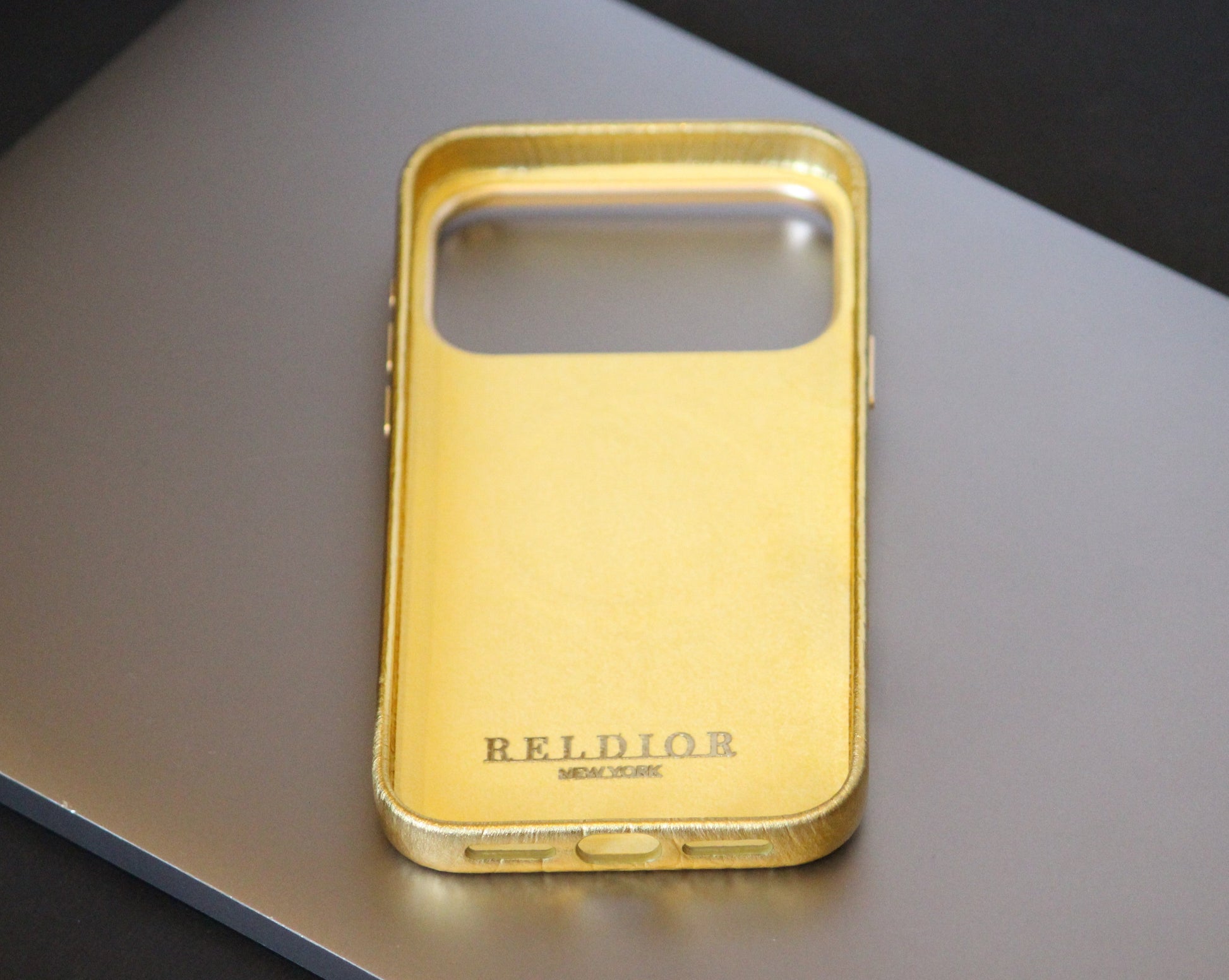 Gold phone case with 'RELIOR' branding on a reflective surface